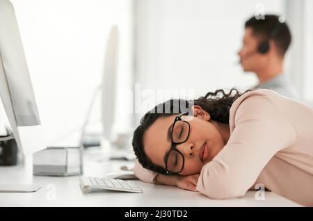 Ein schnelles Nickerchen wird nicht schaden. Aufnahme einer jungen Callcenter-Agentin, die bei der Arbeit ein Nickerchen machte. Stockfoto