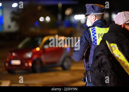 Hamburg, Deutschland. 04. April 2022. Zwei Polizisten stehen am Tatort in der Nähe des beschädigten Unfallwagens. Ein älterer Autofahrer traf einen Polizisten mit seinem Auto während einer Unfalluntersuchung am Montagabend. Der Polizist erlitt Verletzungen und wurde in ein Krankenhaus gebracht, sagte ein Sprecher am Dienstagabend. Die genauen Umstände des Unfalls müsse nun ermittelt werden, sagte er. Quelle: Jonas Walzberg/dpa/Alamy Live News Stockfoto