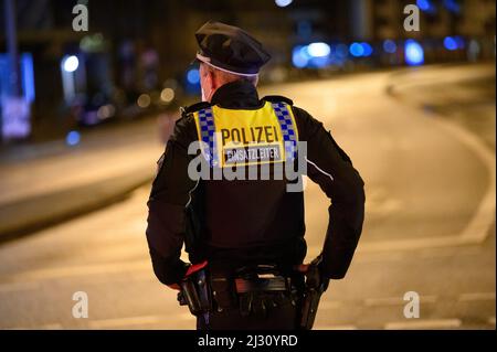 Hamburg, Deutschland. 04. April 2022. Ein Polizeibeamter steht vor einer leeren Straße am Tatort. Ein älterer Autofahrer traf einen Polizisten mit seinem Auto während einer Unfalluntersuchung am Montagabend. Der Polizist erlitt Verletzungen und wurde in ein Krankenhaus gebracht, sagte ein Sprecher am Dienstagabend. Die genauen Umstände des Unfalls müsse nun ermittelt werden, sagte er. Quelle: Jonas Walzberg/dpa/Alamy Live News Stockfoto