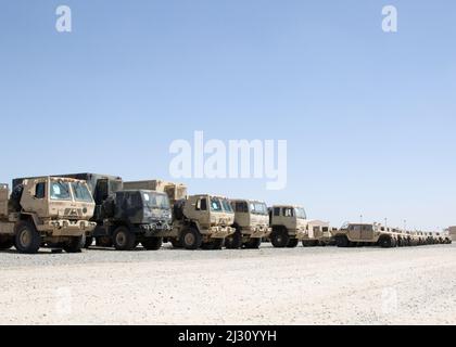 Militärfahrzeuge, die 3. Expeditionary Sustainment Command zugewiesen sind, werden auf einem leeren Parkplatz im Lager Arifjan, Kuwait, am 29. März 2022, abgestellt, wo sie auf den Transport zu einem Hafen warten. „Spears Ready“-Soldaten bereiten die Ausrüstung für den Versand zurück zu ihrer Heimatstation in Fort Bragg, N.C. vor Sie wurden seit August 2021 eingesetzt und besetzen den operativen Kommandoposten des 1. Theatre Sustainment Command. Stockfoto