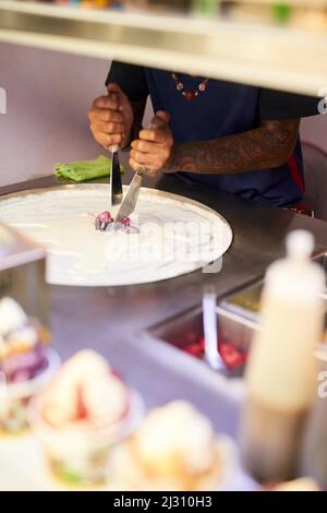 Arbeitet seine Essensmagie. Aufnahme eines nicht identifizierbaren Lebensmittelherstellers, der an einem Marktstand eine Süßigkeit zubereitete. Stockfoto