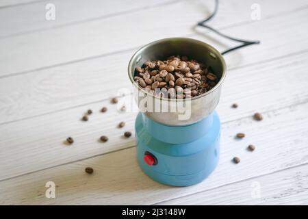 Kaffeebohnen in einer Mühle. Auf weißer Tischplatte mit Platz für Kopien. Stockfoto