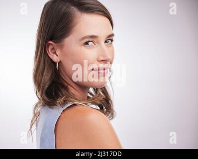 Seien Sie zuversichtlich, wer Sie sind. Studioportrait einer selbstbewussten jungen Frau, die vor grauem Hintergrund posiert. Stockfoto