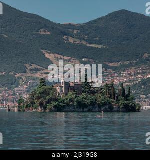 Frau paddelt auf SUP-Bord vor dem Castello della Isola di Loreto Schloss auf der Insel im Iseosee in Italien Stockfoto