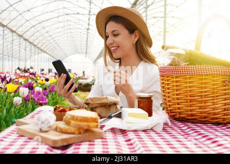 Technologie- und Lifestyle-Konzept. Mädchen teilt online ihre Picknick-Erfahrung auf einer Videokonferenz mit ihren Freunden. Stockfoto