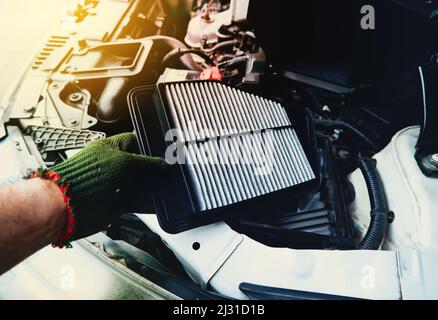 Ein Mechaniker ersetzt einen Luftfilter in der Motorwagenfilterbuchse, Fahrzeugteilekonzept Stockfoto