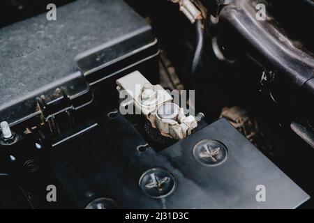 Die Batteriekathodenklemme ist auf einer schwarzen Batterie in einem elektrischen System des Automobilmotors, Automotive Electronics Parts Concept, installiert. Stockfoto