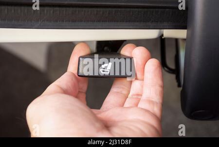 Die Fahrerhand zieht am zweiten Klappknopf im Kofferraum des Fahrzeugs Stockfoto