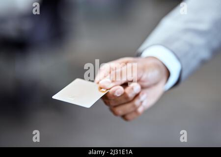 Sie müssen nie wieder Bargeld mit sich führen. Nahaufnahme eines nicht erkennbaren Geschäftsmannes, der eine Kreditkarte in einem Büro hält. Stockfoto