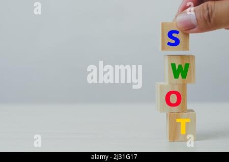 Hand setzen Holzwürfel für SWOT Stärken Schwächen Chancen Bedrohungen auf grauem Hintergrund.Business Marketing Konzept Stockfoto