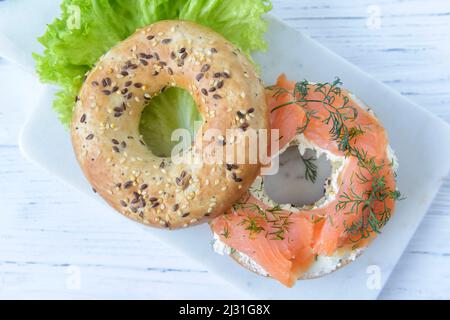 Frischer Multigrain-Bagel mit Frischkäse, Lachsscheiben, Dill und grünem Salat, Draufsicht Stockfoto