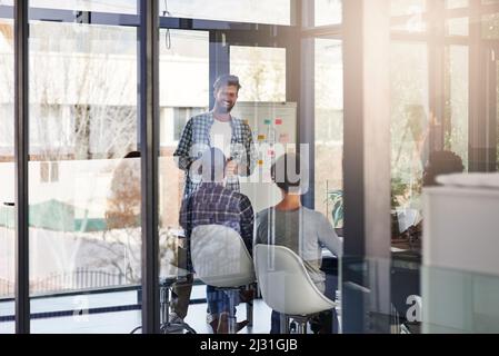 Dem Team eine Aufschlüsselung des Projekts vorlegen. Aufnahme eines Geschäftsmannes, der seine Kollegen in einem Büro vorstellte. Stockfoto