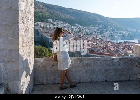 Die Frau blickt von Fort Lovrenijac auf die Altstadt von Dubrovnik, Dalmatien, Kroatien. Stockfoto