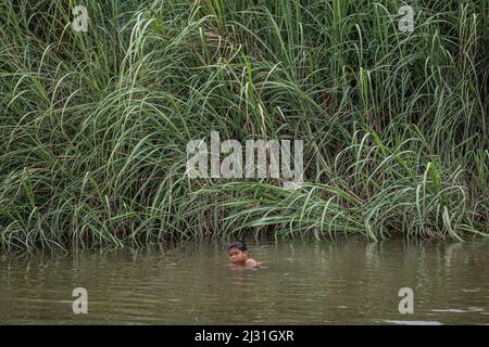 Mae Sot, Thailand. 03. April 2022. Ein Karen-Flüchtling spielt im Moei-Fluss, nachdem er vor den Kämpfen zwischen der Armee von Myanmar (Tatmadaw) und aufständischen Gruppen geflohen ist. Die Kämpfe haben sich seit dem Putsch vom 2021. Februar unter der Führung von General Min Aung Hlaing intensiviert. Flüchtlinge, die vor den Zusammenstößen zwischen den Regierungstruppen und Rebellen in Myanmar fliehen, haben am Ufer des Flusses Moei, der die Grenze zu Thailand bildet, temporäre Lager eingerichtet. Viele leben dort seit über 4 Monaten. Die Flüchtlinge kommen oft während Luftangriffen oder intensiver Kämpfe nach Thailand. Kredit: SOPA Images Limited/Alamy Live Nachrichten Stockfoto