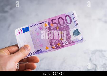 Hand halten und fünfhundert Euro-Banknoten geben. Geld in Menschenhand auf grauem Hintergrund Stockfoto