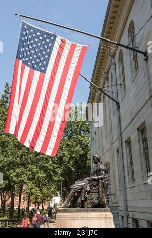 CAMBRIDGE, MA, USA - SEP 13, 2017 : John Harvard Statue unter winkender US-Flagge auf dem Alten Hof der Harvard University. Stockfoto