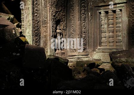 Kopflose apsara-Figur an einer Wand auf dem Ta Prohm Tempelgelände in Siem Reap, Kambodscha. Einst als Drehort für einen Hollywood-Film von 2001 verwendet Lara Croft: Tomb Raider mit Angelina Jolie und vor allem bekannt für seine riesigen Wurzeln aus wilden Bäumen, die tief zwischen den Steinen verwurzelt sind, war Ta Prohm ein Kloster für Studenten des Mahayana-Buddhismus, bevor es verlassen und für Hunderte von Jahren vergessen wurde. Stockfoto