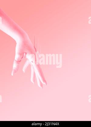 Kreatives Konzept einer erhobenen Hand, die in peachy Farbe in die Luft getaucht wurde. Pastellrosa Hintergrund. Stockfoto