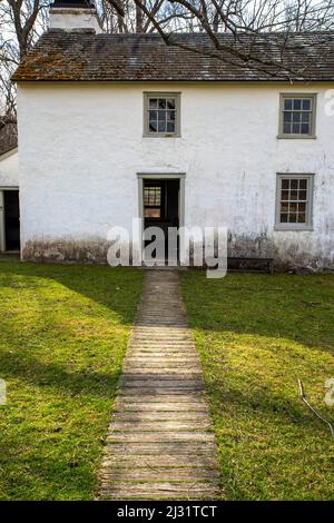Idyllischer Pfad führt durch Gras, um die Tür der weiß getünchten Steinhütte zu öffnen Stockfoto