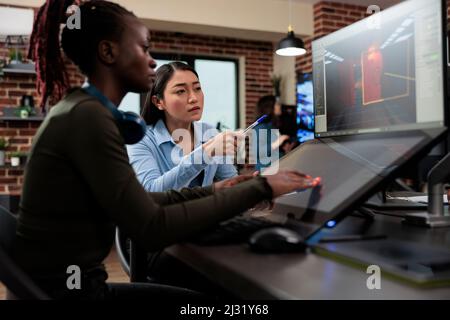 Produktionsabteilung 3D Artist Team Leader mit mehreren Displays auf dem Schreibtisch, die an einem digitalen Entertainment-Projekt arbeiten. Game Entwicklung kreative Firma Mitarbeiter arbeiten an Videospiel-Level-Design. Stockfoto