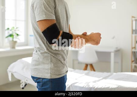 Bandage am Ellbogen eines unbekannten Mannes, den er trägt, um Gelenkschmerzen wiederherzustellen und zu lindern. Stockfoto