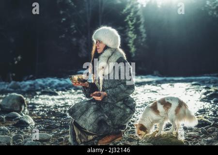 Schöne schamanische Mädchen spielen auf tibetische Schüssel in der Natur. Stockfoto