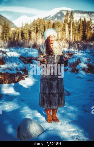 Schöne schamanische Mädchen spielen auf tibetische Schüssel in der Natur. Stockfoto