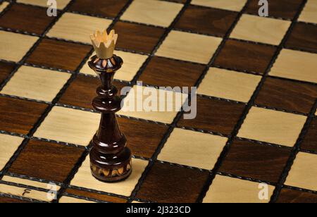 Schwarzer König, der auf einem Schachbrett steht Stockfoto