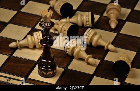 Schwarzer König, der auf einem Schachbrett vor weißen Bauern steht Stockfoto