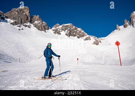 Junger Skifahrer mit Stöcken, die am verschneiten Berghang im Winterresort stehen Stockfoto