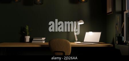 Moderner, dunkler skandinavischer Büroarbeitsplatz mit Laptop-Computer, weißem Bildschirm, Modell unter Tischlampen und Zubehör auf Holztisch. Workspa Stockfoto