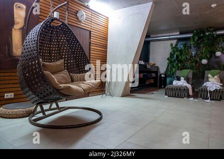 Leerer Schaukelstuhl, der im Spa-Center an der dekorierten Wand aufgehängt wurde Stockfoto