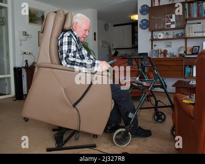 Niederlande, ein stabiler Mann sitzt in einem Aufzugsstuhl in seinem Haus, so dass er leicht aufstehen und mit seinem Rollator weiter gehen kann. Die Aufzüge sind Stühle Stockfoto