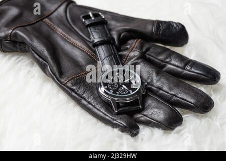 Herren Accessoires auf weißem Hintergrund. Nahaufnahme einer Luxus-Herrenuhr mit schwarzem Zifferblatt und Lederarmband. Stockfoto