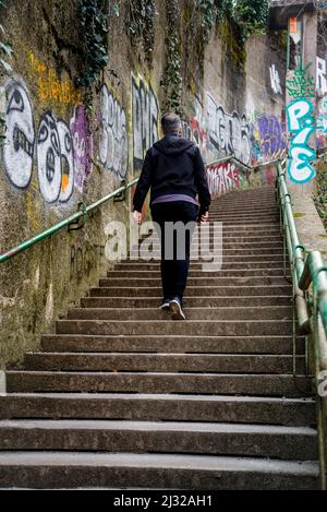 Mann, der die Treppe nach Rokov Perivoj hinaufgeht, vorbei an mit Graffiti bedeckten Wänden, Zagreb, Kroatien Stockfoto