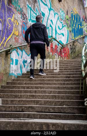 Mann, der die Treppe nach Rokov Perivoj hinaufgeht, vorbei an mit Graffiti bedeckten Wänden, Zagreb, Kroatien Stockfoto