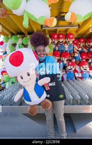 Eine Teenager aus Brooklyn beginnt ihren Sommerjob, indem sie an den Frühlingswochenenden an einem Geschicklichsspiel im Luna Park arbeitet. In Coney Island, Brooklyn, New York City. Stockfoto