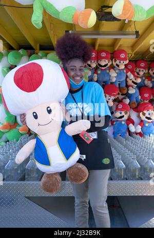 Eine Teenager aus Brooklyn beginnt ihren Sommerjob, indem sie an den Frühlingswochenenden an einem Geschicklichsspiel im Luna Park arbeitet. In Coney Island, Brooklyn, New York City. Stockfoto