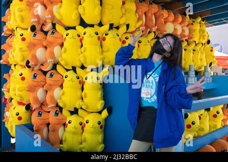 Eine Teenager aus Brooklyn beginnt ihren Sommerjob, indem sie an den Frühlingswochenenden an einem Geschicklichsspiel im Luna Park arbeitet. In Coney Island, Brooklyn, New York City. Stockfoto