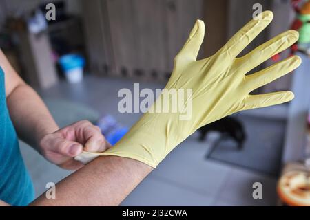 Junger Mann mit gelben Gummihandschuhen. Bereit zum Reinigen Stockfoto