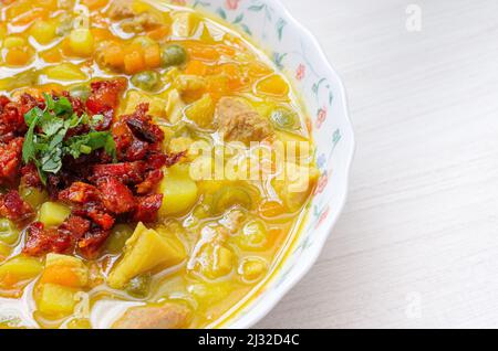 Teller mit Kuttelsuppe, genannt Mondongo, traditionelles Essen aus Kolumbien, Südamerika, auf hellem Holz. Stockfoto