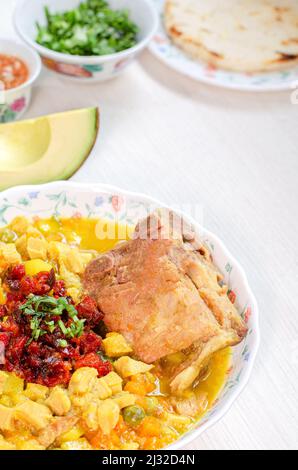 Teller Suppe mit Kutteln und Backbone Schweinefleisch, genannt Mondongo, traditionelle Lebensmittel aus Kolumbien, Südamerika, auf hellem Holz. Callos, mondongo, guatita, Tri Stockfoto