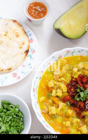 Teller mit Kuttelsuppe, genannt Mondongo, traditionelles Essen aus Kolumbien, Südamerika, auf hellem Holz. Stockfoto