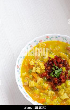 Teller mit Kuttelsuppe, genannt Mondongo, traditionelles Essen aus Kolumbien, Südamerika, auf hellem Holz. Stockfoto