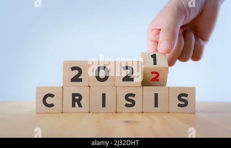 Krisenmanagementkonzept im neuen Jahr 2022 . Unerwartete Auswirkungen auf die Situation von Unternehmen und Leben. Hand dreht Holzwürfel 2021 bis 2022 mit dem Text "KRISE Stockfoto