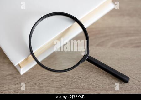 Bildungs- und Forschungskonzept - Nahaufnahme von Buch und Lupe auf dem Tisch Stockfoto