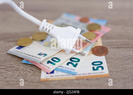 Stromkosten und teures Energiekonzept - Stromversorgung Netzkabelstecker mit Euro-Banknoten und Münzen Stockfoto