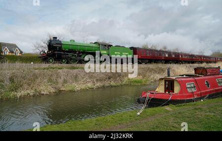 Die LNER Thompson Class B1 Mayflower fährt an einem schmalen Boot auf dem Kennet- und Avon-Kanal in der Nähe von Great Bedwyn in Wiltshire vorbei, während sie sich auf einem von Steam Dreams organisierten Tagesausflug von London nach Bath aufmacht. Bilddatum: Dienstag, 5. April 2022. Stockfoto