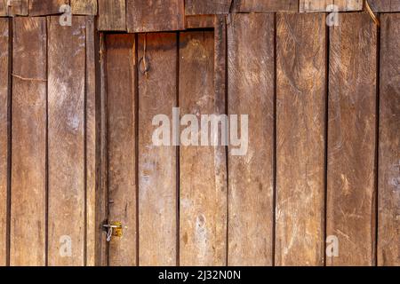 Einfaches Haus in diesem Dorf. Hergestellt mit Holzbrettern oder Lattenrosten für Wände und Türen. Dies ist ein Blick darauf, wie die Tür und die Gebäudewand gebaut werden. Stockfoto