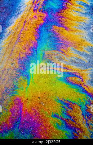 Viele Farben, die durch ein Ölleck auf nasser Straße entstehen. Stockfoto